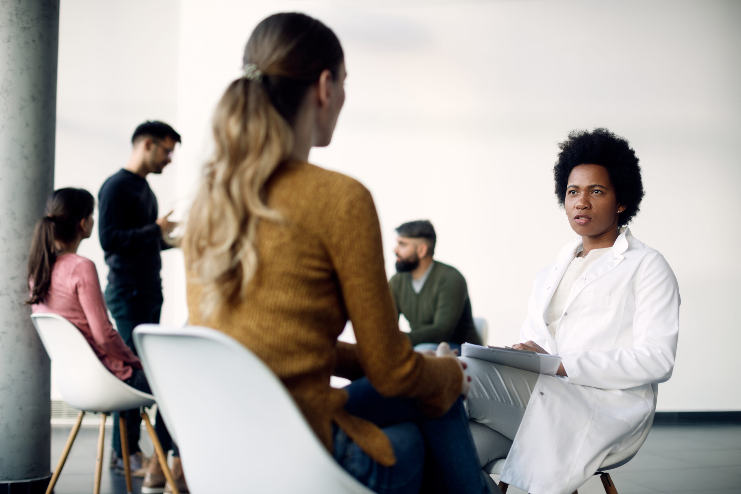 African American psychotherapist communicating with female patient before group session at medical center.