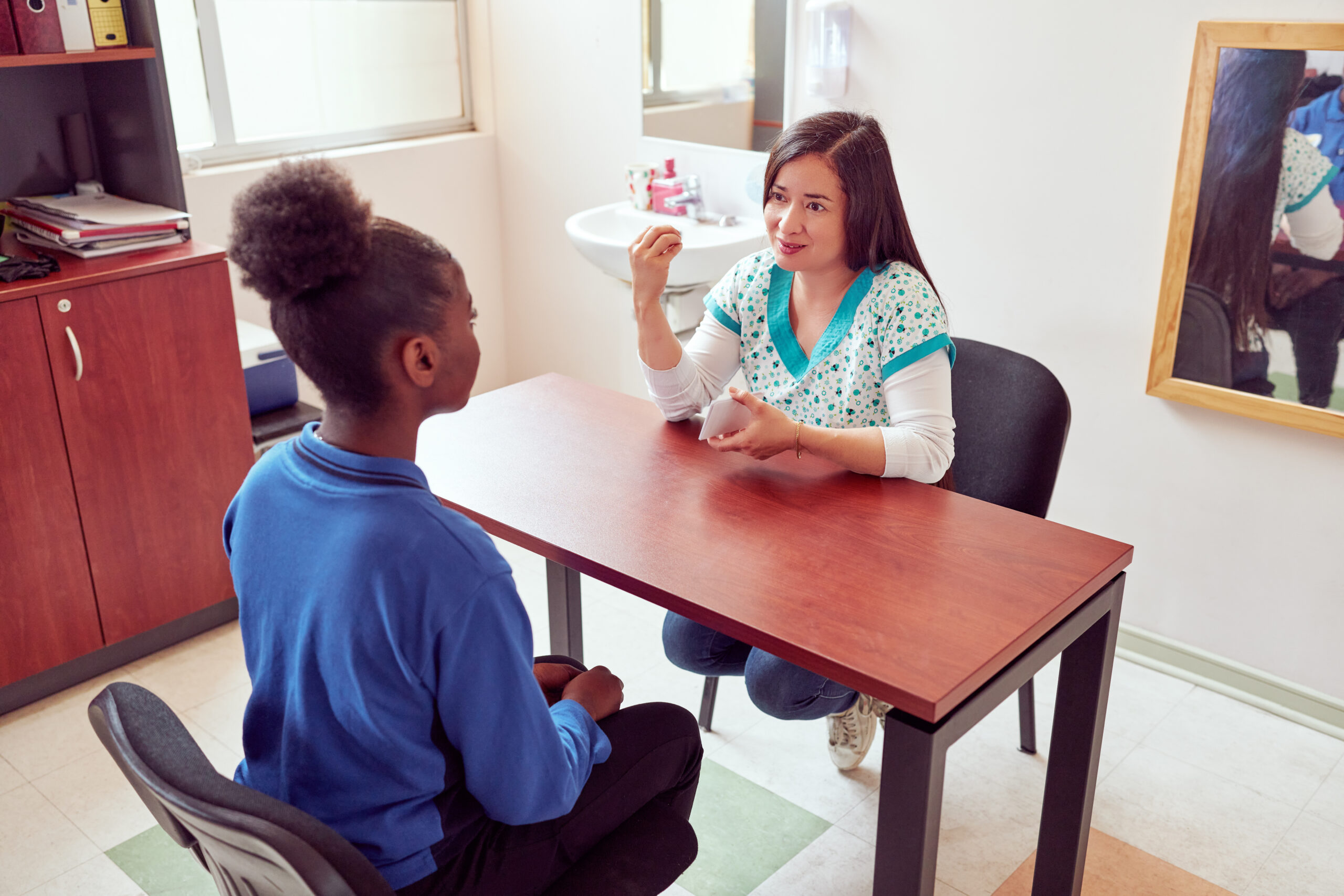 speech therapist working with playing cards with black teenage secondary school student
